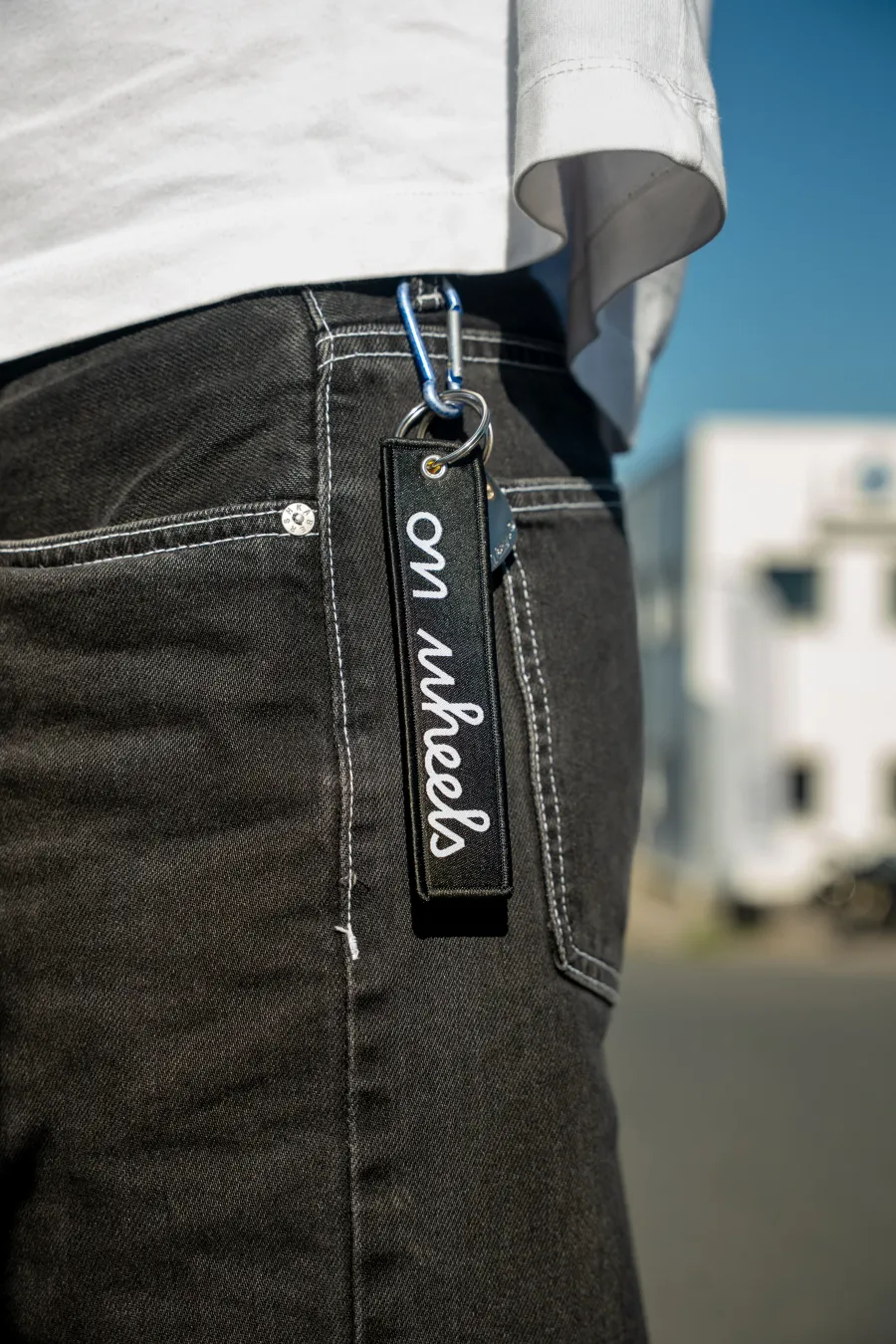 Porte-clés On Wheels accroché à un jean avec mousqueton, accessoire motard du quotidien